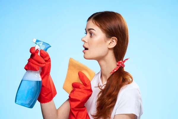 Donna con prodotti per la pulizia nelle mani del servizio professionale consegna sfondo blu — Foto Stock