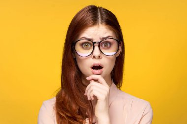 Gözlüklü gülümseyen kadın. Cazibeli yüz. Kolları sarı arka plan lüksü.