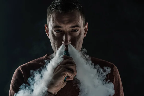 Un hombre fuma un vapor sobre un fondo negro retrato de vapor de humo blanco de cerca — Foto de Stock