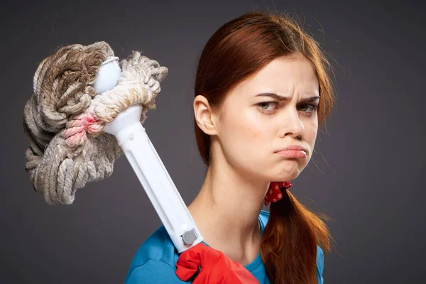 Disgruntled cleaning lady tired cleaning mop in hand dark background — Stock Photo, Image