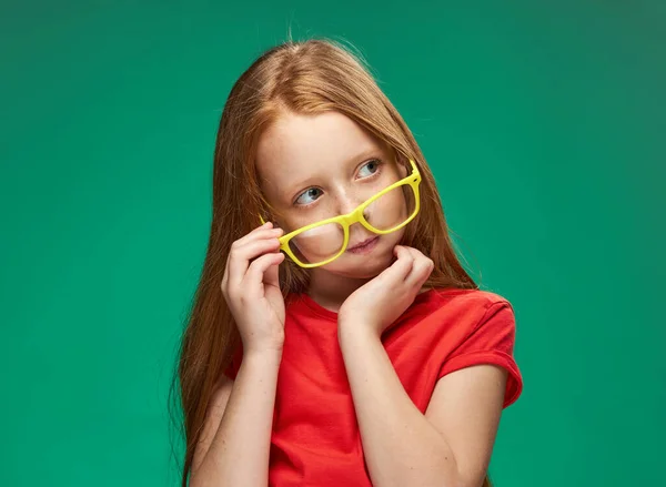 Lány piros haj visel sárga szemüveg pózol érzelmek vágott kilátás stúdió iskola — Stock Fotó