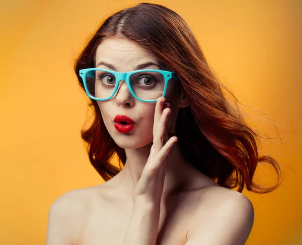 Happy woman in blue glasses with bright makeup on orange background — Stock Photo, Image