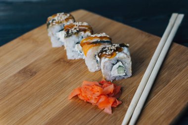 Sushi kırmızı zencefilli çubukları yuvarlıyor tahta tahtaya yakın plan