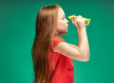 Kırmızı saçlı, kırmızı tişörtlü, sarı gözlüklü, neşeli bir kız.