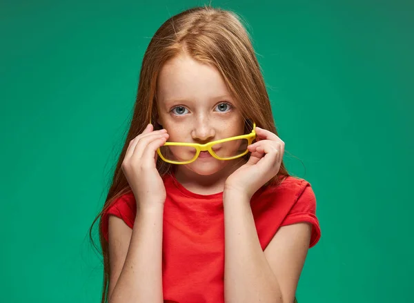 Aranyos lány piros haj szemüveg oktatás iskola zöld háttér — Stock Fotó