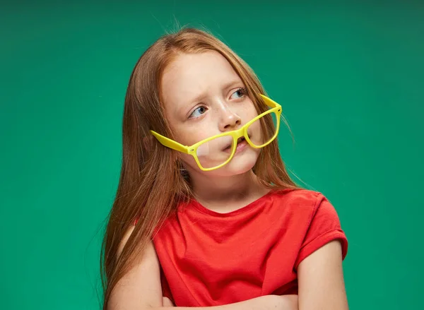 Vidám vörös hajú lány sárga szemüveg érzelmek zöld háttér gyermekkor — Stock Fotó