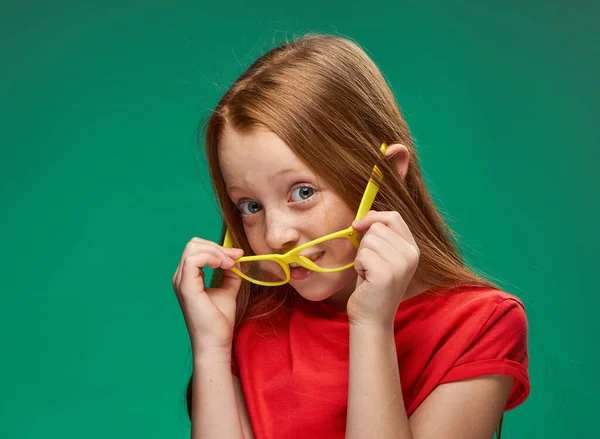 Χαρούμενα κόκκινα μαλλιά κορίτσι κίτρινα γυαλιά συναισθήματα πράσινο φόντο παιδική ηλικία — Φωτογραφία Αρχείου