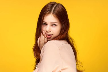 Güzel bir kadın, çekici. Duygularına bak. Yüzü sarı arka plana yakın.