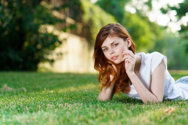 Kadın çimenlerin üzerinde uzanıyor. Park yeri, temiz hava.