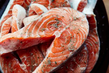 Tabakta dilimlenmiş kırmızı balık, ahşap deniz mahsulleri pişiriyor.