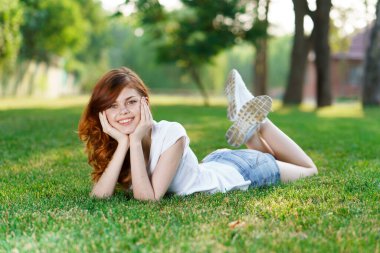 Neşeli kadın bahçedeki çimlerde uzanıyor. Açık hava eğlence doğası.