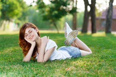 Neşeli kadın parkın bahçesinde uzanmış dinleniyor.