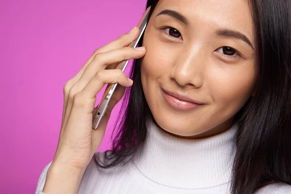Женщина азиатская появление говорить по телефону крупным планом студии розовый фон улыбка — стоковое фото