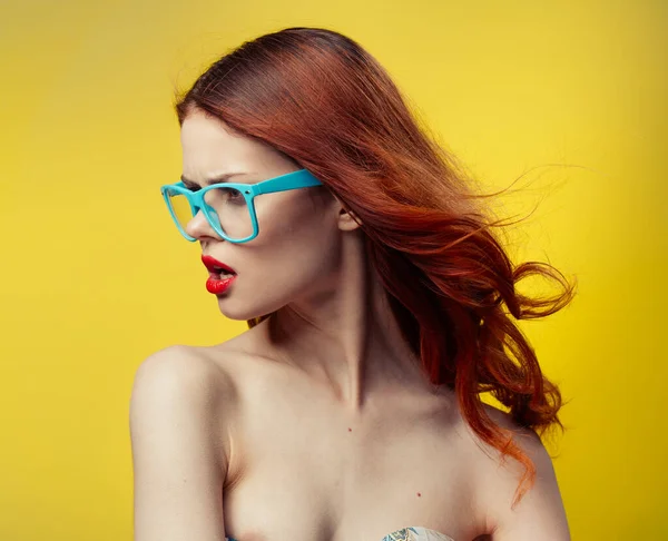 Woman in blue glasses on a yellow background portrait — Stock Photo, Image