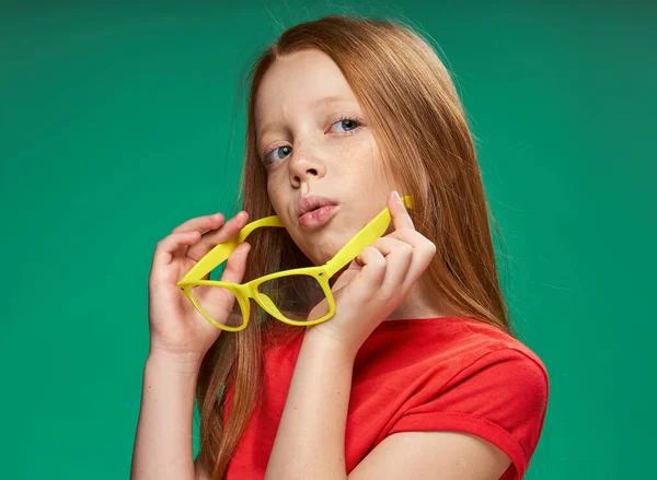 Рыжеволосая девушка эмоции желтые очки студии зеленый фон — стоковое фото