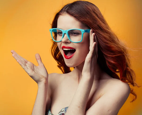 Happy woman in blue glasses with bright makeup on orange background — Stock Photo, Image