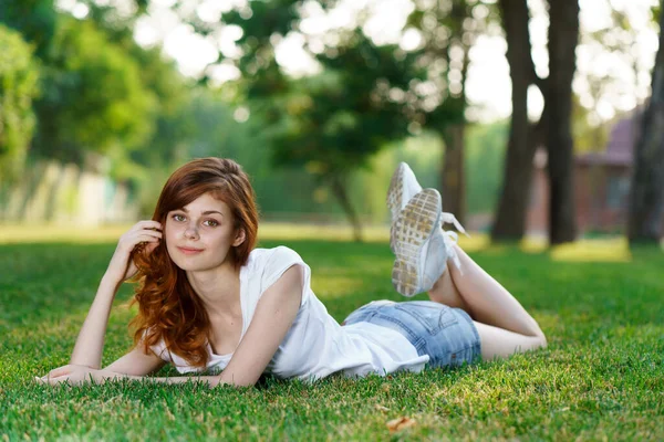 Fröhliche Frau liegt auf der Liegewiese im Park — Stockfoto