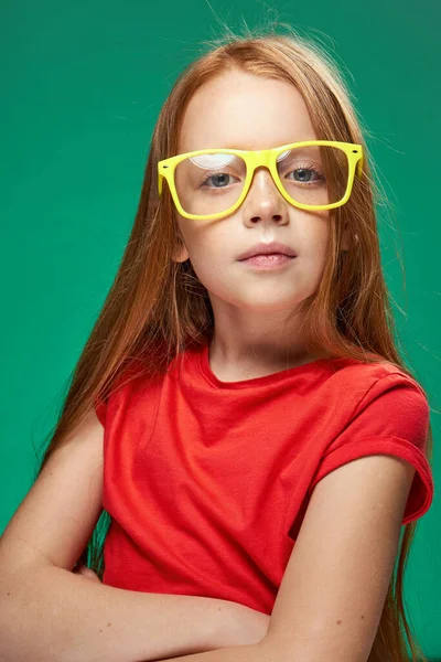 Aranyos vörös hajú lány szemüveges gesztikuláló kezével iskola gyermekkori zöld háttér — Stock Fotó