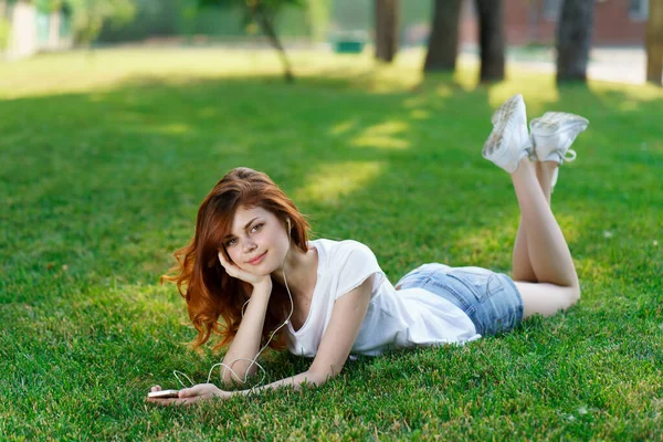 Rothaarige Frau liegt im Park auf dem Rasen an der frischen Luft — Stockfoto