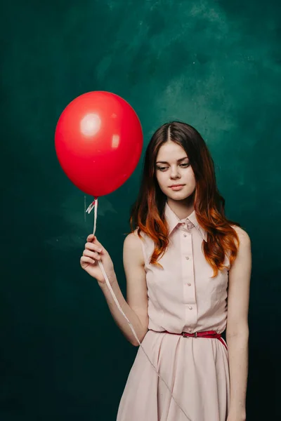 Kvinna med en röd ballong på en grön bakgrund rosa klänning modell — Stockfoto