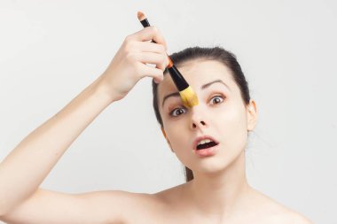 Esmer, çıplak omuzlu. Cilt bakımı prosedürlerini uyguluyor.