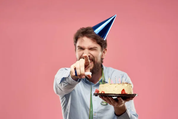 Hombre con pastel en un plato y en una camisa azul sobre un fondo rosa cumpleaños vacaciones vista recortada — Foto de Stock