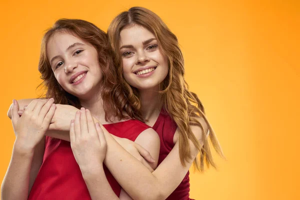 Mutter und Tochter in roten Kleidern Unterhaltung Lebensstil gelben Hintergrund — Stockfoto