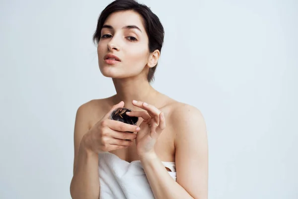 Hübsche Frau in weißem Handtuch nackte Schultern schwarze Creme in den Händen Hautpflege Spa-Verfahren — Stockfoto