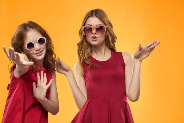 Vrolijk mam en dochter dragen zonnebril levensstijl vriendschap familie geel achtergrond studio — Stockfoto