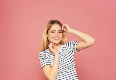 Pembe arka planda tişört giymiş güzel bir sarışındı.