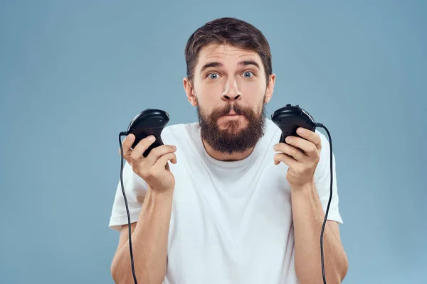 Un hombre en una camiseta blanca con un joystick en las manos consola de juegos emociones de entretenimiento —  Fotos de Stock