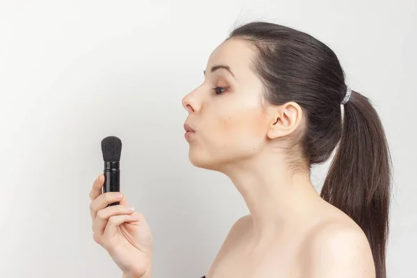 woman applying mask with makeup brush to face naked shoulders skincare