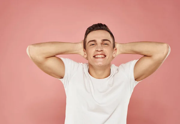 Emotionaler Mann im weißen T-Shirt gestikuliert mit geschnittenen Händen Blick rosa Hintergrund — Stockfoto