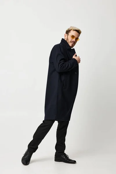 Hombre guapo en abrigo negro sonrisa gafas amarillas longitud completa — Foto de Stock