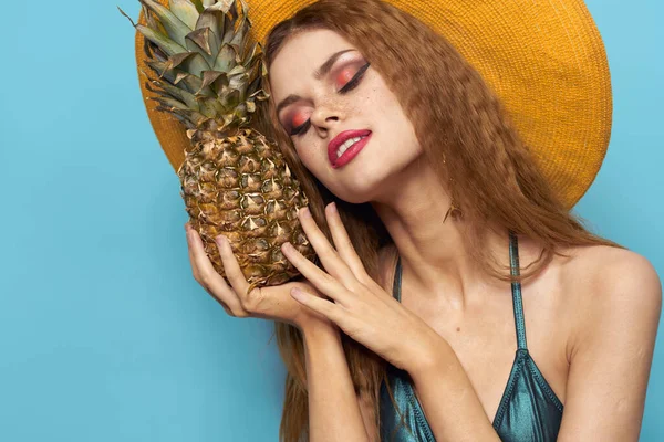 Kvinna i strand hatt ananas innehav baddräkt exotiska frukter blå bakgrund semester — Stockfoto