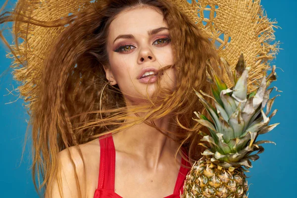 En kvinna i halmhatt med en ananas i händerna eller är det en rolig blå exotisk frukt bakgrund — Stockfoto