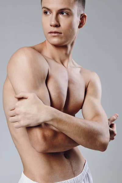 Atleta con i muscoli pompati premere bodybuilder sfondo grigio — Foto Stock