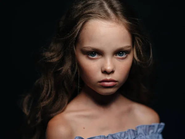 A menina olha para a frente severamente contra um fundo escuro em um vestido de verão — Fotografia de Stock