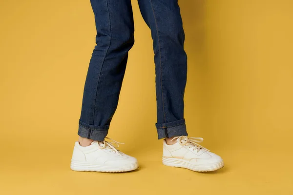 Sapatos na moda branco tênis pernas amarelo fundo recortado vista — Fotografia de Stock