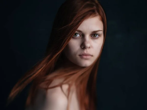 Vista de cerca recortada de una mujer con el pelo rojo mirando hacia adelante sobre un fondo negro —  Fotos de Stock