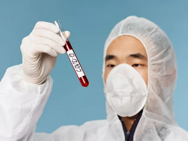 Азіатський чоловік медична маска аналіз крові крупним планом огляд синього фону діагностика — стокове фото