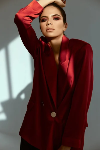 Jolie femme tenant la main sur sa tête veste rouge mode posant Studio — Photo