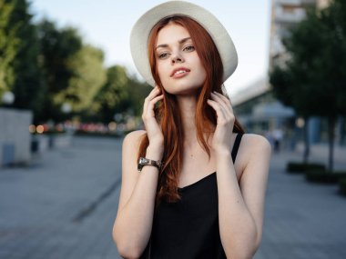 Binanın yanındaki sokakta siyah elbiseli, güzel kızıl saçlı kadın.