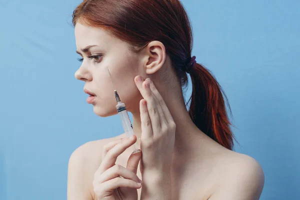 Femme tenant la seringue près du visage rajeunissement botox injection fond bleu — Photo