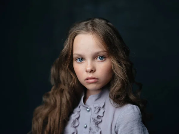 Portré egy gyönyörű lány egy szürke ruha egy sötét háttér és göndör haj kék szeme — Stock Fotó