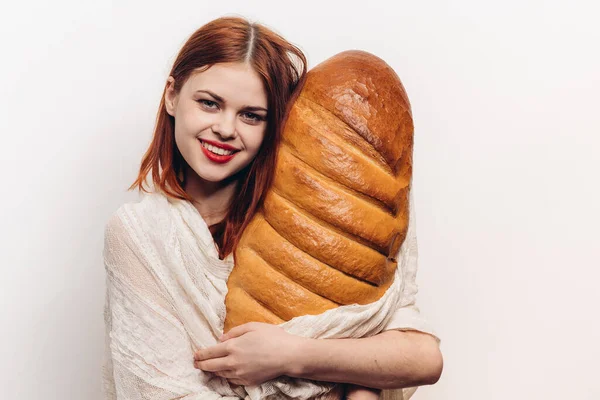 Happy red-haired woman with loaf in hands on light background cropped view — Stock Photo, Image