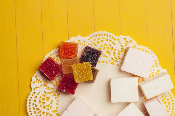 Marmelada doces doces multicoloridos sobremesa de chocolate em um fundo amarelo — Fotografia de Stock