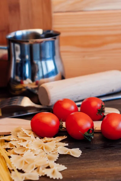 Cherry rajčata těstoviny kuchyňské nádobí dřevěný stůl italská kuchyně — Stock fotografie