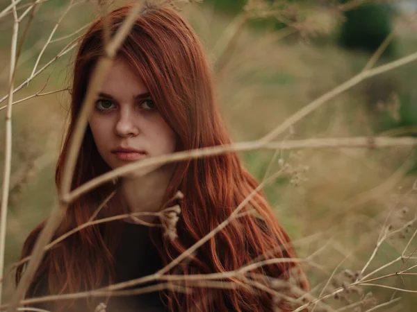 Romantická žena v černých šatech v blízkosti suché trávy na čerstvém vzduchu přírodní louka — Stock fotografie