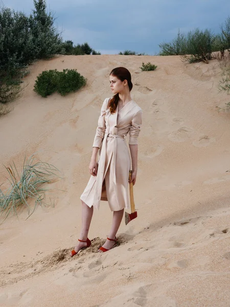 Uma mulher bonita em um vestido de verão e sapatos vermelhos com um machado nas mãos — Fotografia de Stock